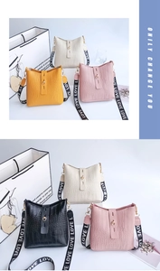 Detail of crocodile embossed bucket bag with LOVE patterned wide woven strap