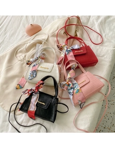 Detail of four colorful faux crocodile leather mini bags with silk scarves and gold logo