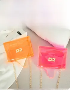 Detail of colorful transparent PVC crossbody bags with golden metal chain and twist lock