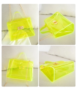 Detail view of transparent neon PVC jelly bag featuring gold chain and turn-lock closure