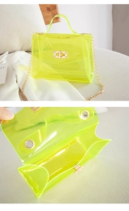 Detail of neon green transparent PVC jelly bag featuring gold chain and turn-lock closure