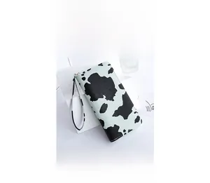 Close-up of mint green cow pattern long wallet with zipper and wrist strap detail