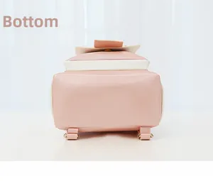Détail du bas du sac à dos en cuir rose et blanc avec boucles métalliques et sangles