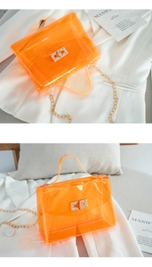 Detail view of orange transparent PVC mini bag with golden metal lock and chain strap