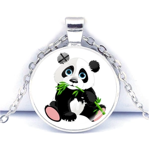Gros plan d'un pendentif rond argenté avec un adorable panda mangeant du bambou