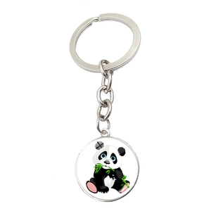 Detail of a silver metal keychain with a round panda charm eating bamboo on a white background