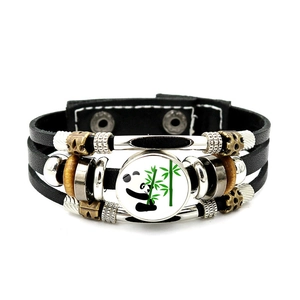 Detail eines mehrlagigen schwarzen Lederarmbands mit Panda-Glas-Charm und Perlen