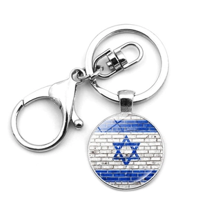 Detail of metal keychain with Israel flag pendant on white brick texture background