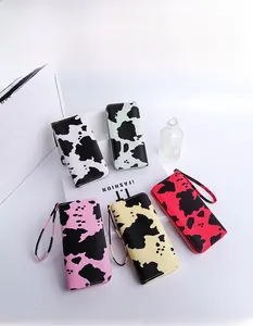Flat lay of multiple colorful cow print long wallets with wrist straps and zippers