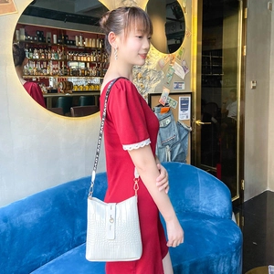 White crocodile pattern bucket bag with contrast LOVE strap worn by a model