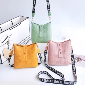 Three crocodile embossed bucket bags in yellow, green, and pink with LOVE straps