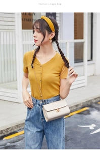 Modella asiatica con borsa beige a tracolla trapuntata e catena dorata in stile urbano