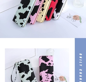 Detail view of colorful cow print long wallets with wrist straps and metal zippers