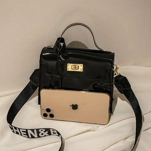 Black patent leather mini crossbody bag with wide letter strap and gold hardware clasp