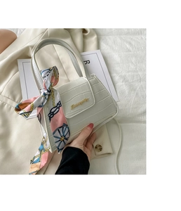 Detail of white crocodile texture handbag with gold metal plaque and floral silk scarf