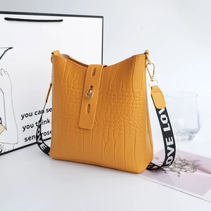 Yellow crocodile pattern bucket bag with LOVE letter strap in a lifestyle setting