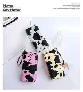 Detailed view of long cow print wallets in pink, green and yellow with wrist straps