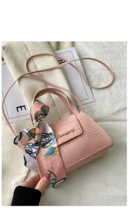 Detailed macro view of pink crocodile pattern PU leather bag with silk scarf and logo