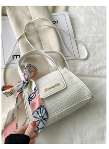 Detail of white crocodile embossed small square bag with silk scarf and gold logo