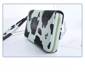 Detail view of cow print long wallet with mint green zipper and gold hardware accent
