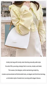 Detail of elegant color-block leather tote bag featuring gold lettering and slim shoulder strap