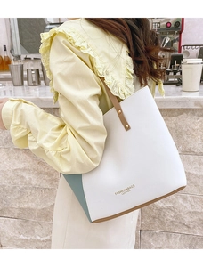 Detail showing the white and blue color-block tote bag with a brown leather shoulder strap