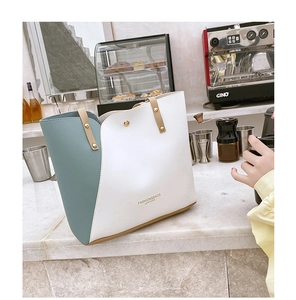 Close-up of color-block tote bag with gold rivets on a marble cafe tabletop
