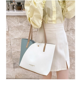 Detail showing white and blue tote bag with leather handles and fashion lettering