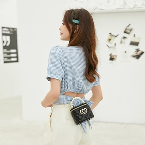 Black quilted bucket bag with pearl handle and heart buckles on a stylish model