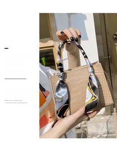 Detail der khakifarbenen Handtasche mit Krokodilmuster und elegantem Seidenschal am Griff