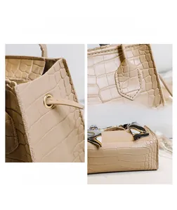 Detailansicht der beigen Handtasche mit Kroko-Prägung, Metallösen und geometrischem Seidenschal