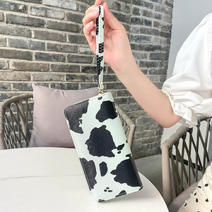 Women's long clutch bag with black and white cow print and removable wrist strap