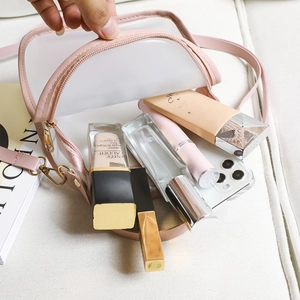 Minimalist transparent PVC semi-circle crossbody bag with pink leather trim and gold zipper