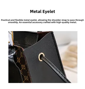 Close-up of golden metal eyelet and slim shoulder strap on dark printed leather handbag