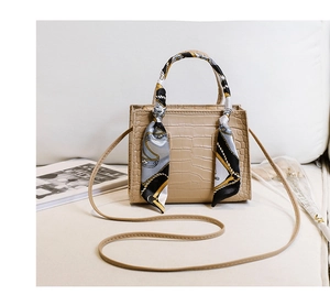 Detail der beigen Handtasche mit Krokodilmuster und elegantem Seidentuch am Griff