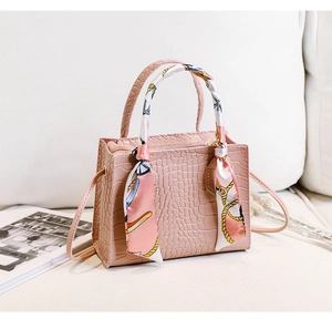 Detail der rosa Kunstledertasche mit Kroko-Prägung und dekorativem Seidenschal-Griff