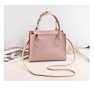 Detailaufnahme einer rosa Krokodil-Handtasche aus Kunstleder mit dekorativem Seidenschal