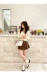 Quilted tote bag with silk scarf on handle paired with knit cardigan and pleated skirt