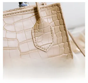 Nahaufnahme der Krokodilprägung und der präzisen Nähte der beigen Handtasche
