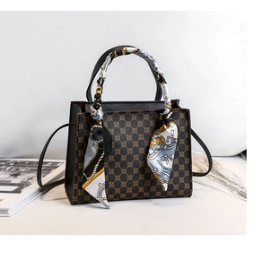 Detailed view of structured handbag with patterned silk scarf wrapped on the handle