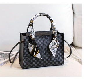 Detail of black tote bag with geometric logo pattern and elegant printed handle scarf