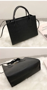 Detail of black lychee grain leather tote bag with metal hardware and dual strap design
