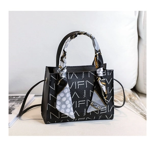 Close-up of black lychee texture tote bag with white lettering and decorative silk scarf