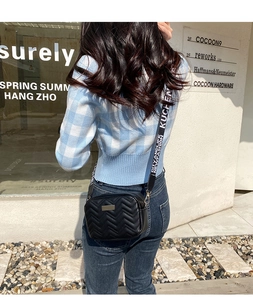 Detail of V-shaped quilted camera bag with wide letter-printed shoulder strap