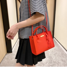 Litchi pattern orange crossbody bag styled on a model with houndstooth shirt