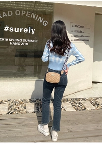 Outdoor street view of beige quilted crossbody bag with jacquard wide shoulder strap