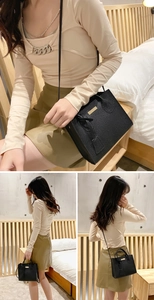 Close-up of black pebble grain leather tote bag with elegant gold metal plate detail