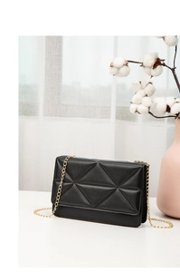 Detail of black geometric quilted crossbody bag with elegant gold metal chain strap
