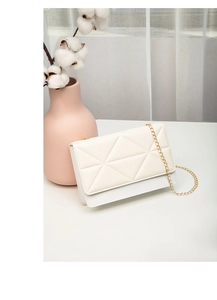 Detail of ivory quilted crossbody bag featuring geometric stitching and gold chain strap