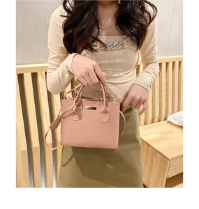 Detail of light pink lychee pattern leather square handbag featuring silver metal plate